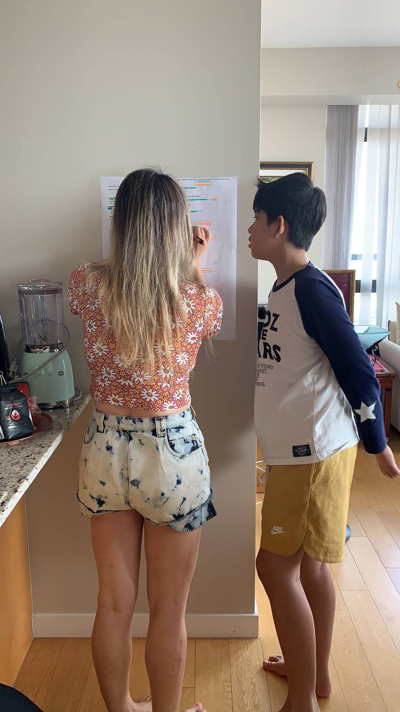 An assistant teaching English at a wall chart