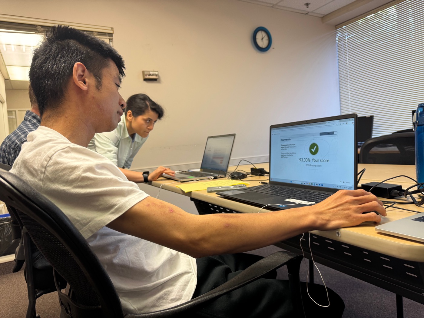 An assistant beside a client passing a certification test
